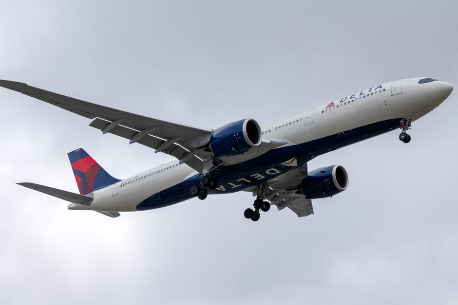 Delta Airlines aircraft in descent over Los Angeles, cloudy sky.