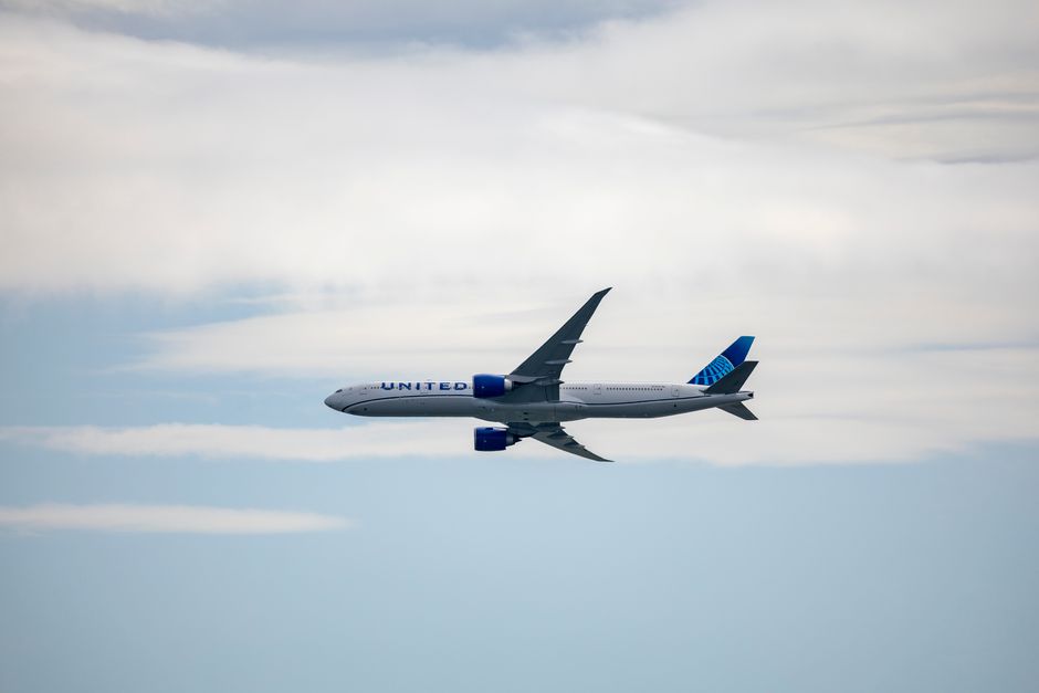 A United airplane soaring in the sky amidst clouds, showcasing modern aviation.