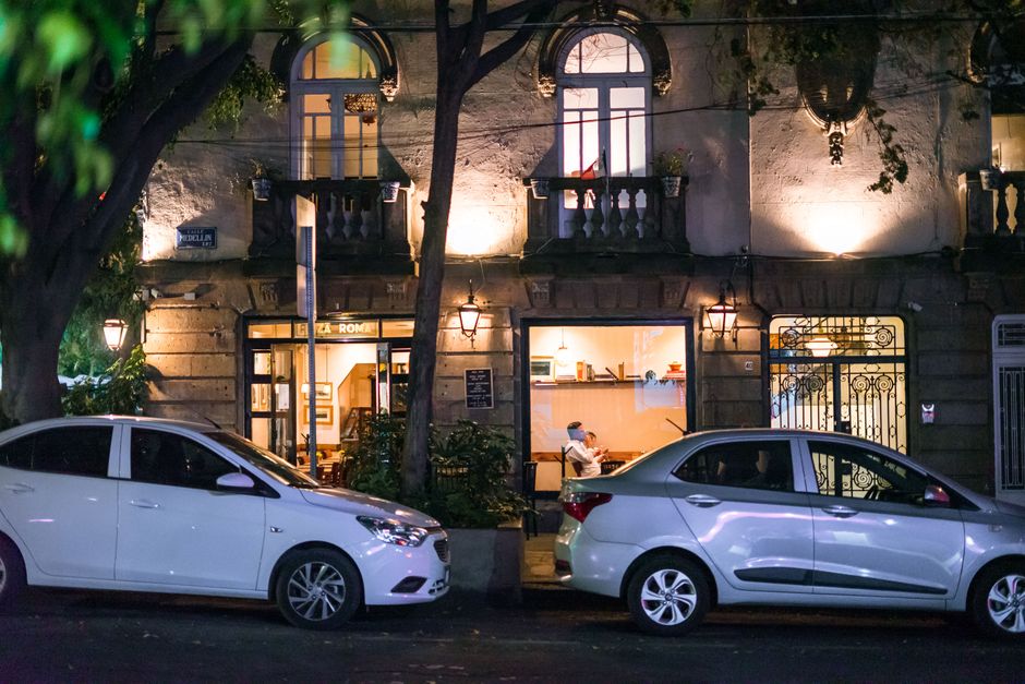 Illuminated café scene on a quiet street in Ciudad de México with parked cars.