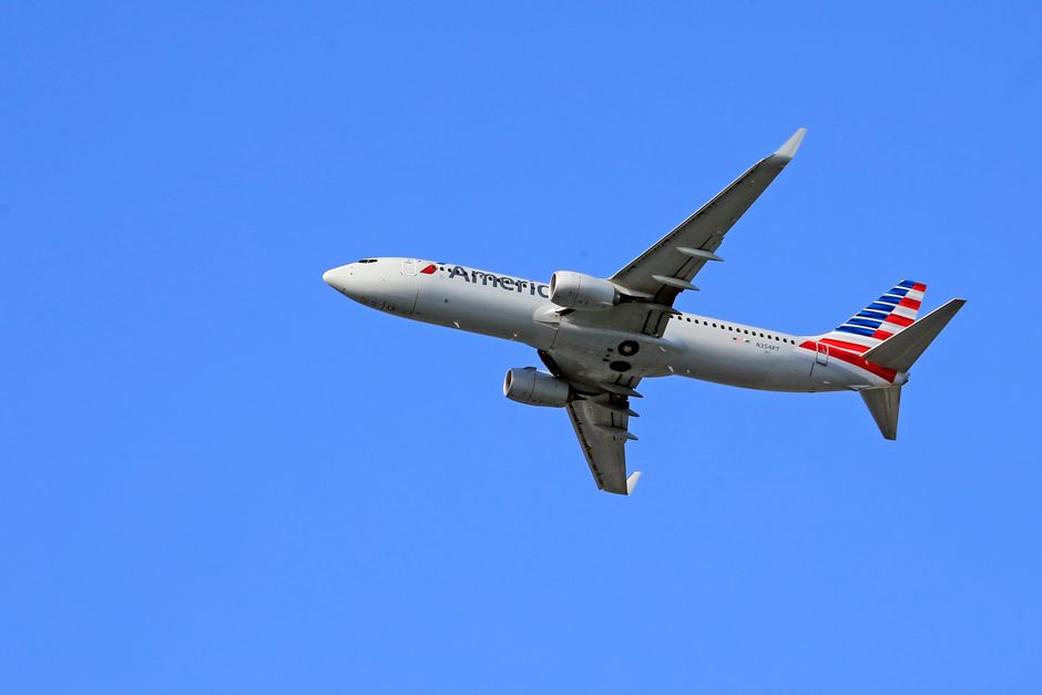 Boeing 737 aircraft flying under a clear blue sky, showcasing aviation in motion.