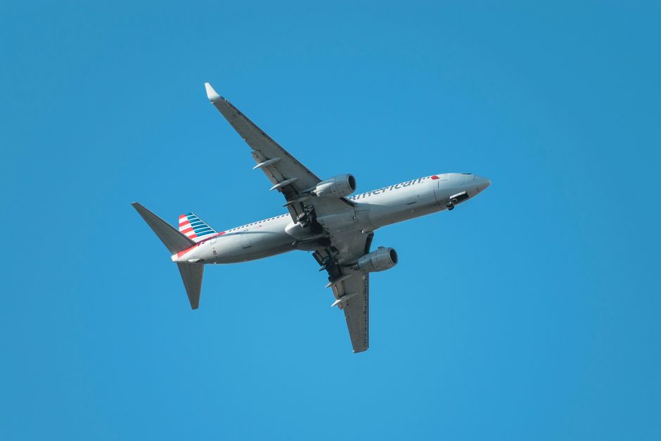 An American commercial airplane flying against a clear blue sky.